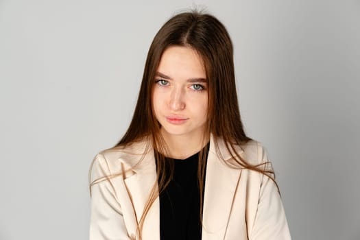 Young Woman in White Jacket and Black Pants on Gray Background.close up