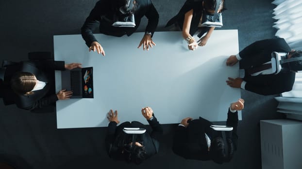 Top down aerial view of professional business team wear vr headset to enter virtual world while sitting and using hand gestures to manipulate the data from the manager laptop. Technology. Directorate.