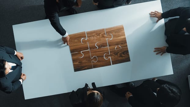 Top view of business people putting jigsaw together at meeting room. Professional marketing team standing at table while gathering puzzle piece. Show unity, cooperation and team working. Directorate.