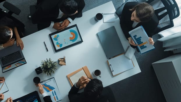 Top view of smart executive manager holding stock market investment chart while planning marketing strategy with diverse group. Smart business team brainstorming and working together. Directorate.