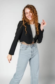 Joyful Young Woman Dancing Alone in Light-Colored Casual Attire Against a Grey Background close up