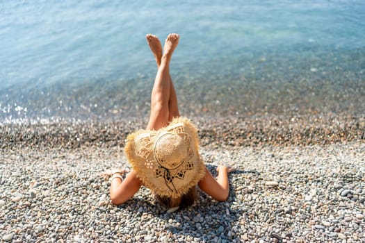 Beach Relaxation woman lies on a pebble beach, legs raised, and arms spread out. The concept of travel, vacation at sea.