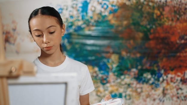 Multicultural student paint the canvas together in art lesson with colorful stained wall. Closeup of african boy and caucasian girl drawing picture or doing creative activity together. Edification.