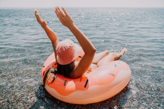 Summer Vacation Woman in hat floats on an inflatable donut mattress, a water toy swim ring. Unrecognizable young woman relaxing and enjoying family summer travel holidays vacation on the sea