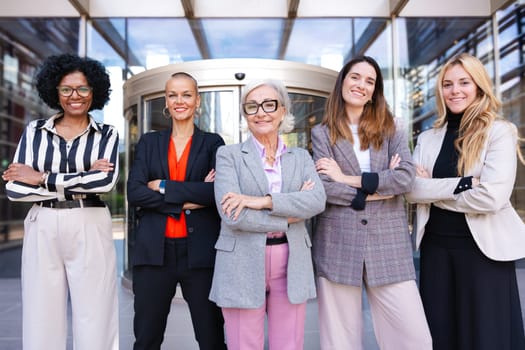 Five businesswomen standing side by side with their arms crossed looking at the camera smiling. Suitable for team, friendship and diversity concepts.