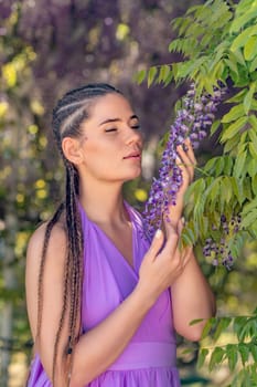 Woman wisteria lilac dress. Thoughtful happy mature woman in purple dress surrounded by chinese wisteria.