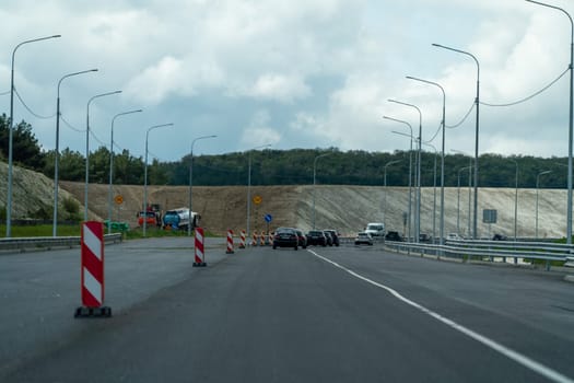 A road with a red and white cone on the side of it. The road is empty and there are no cars on it