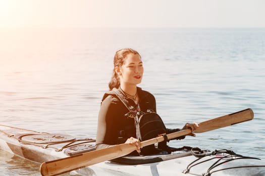 Happy smiling woman in kayak on ocean, paddling with wooden oar. Calm sea water and horizon in background