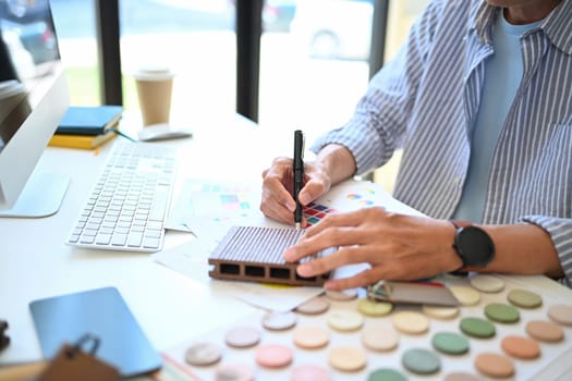 Cropped shot of senior male decorator working with material sample board at his office.