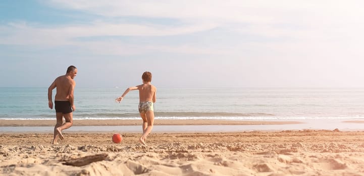 Father and son running on the beach with copy space. Playful casual family enjoying