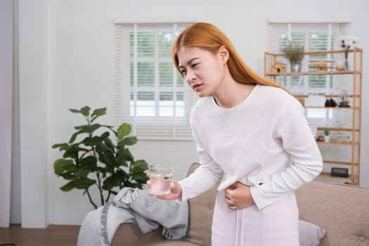 A young woman with stomach pain from diarrhea or menstrual cramps felt sick and touched her stomach with an unhappy expression..