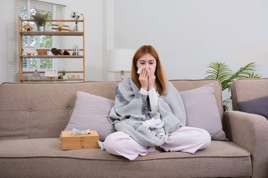 Young Asian woman with cold and allergies feels sick and sneezes on a day of resting at home..