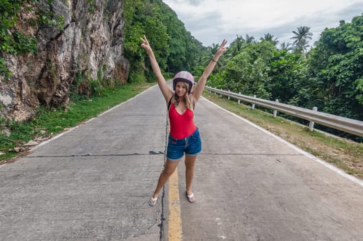 Young woman posing on a scenic mountain road in tropical setting during daytime