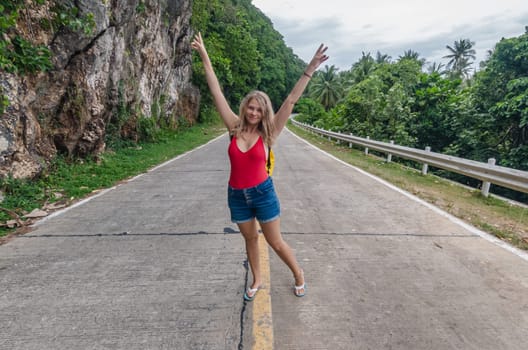 Young woman posing on a scenic mountain road in tropical setting during daytime