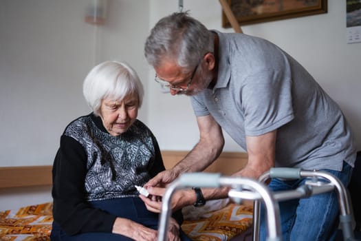 Man is helping an elderly woman with everyday tasks, helping with technology, setting video face time with her family using smart phone