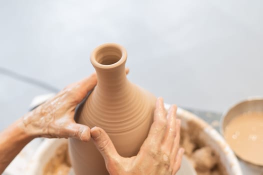 Close-up of a potter's hands making a ceramic vase on a potter's wheel