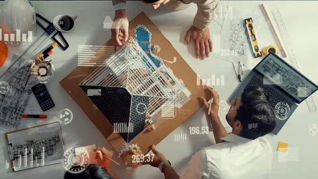 Top view of engineer inspect house model and writing note book. Aerial view of skilled manager checking and looking at building construction with financial statistic graph holographic.. Alimentation.