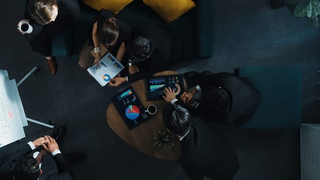 Top down view of business people listen businessman present idea while making decision. Group of diverse team making a decision to invest start up project while hold tablet display graph. Directorate.