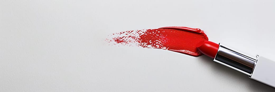 An open red lipstick creates a swatch on a white surface, leaving behind a smear of classic red matte lipstick.
