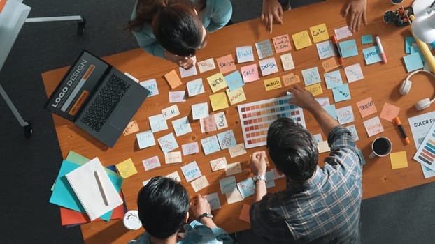 Time lapse of business team with casual outfit looking laptop screen and sharing idea. Aerial view of manager working and checking color palette at table with sticky notes and headphone. Symposium.