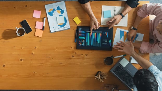 Executive manager explain financial graph to colleague at meeting room. Top aerial view of diverse marketing team sharing idea and planning strategy while sitting at table with tablet. Convocation.