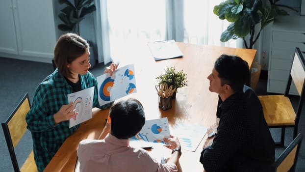 Top view of diverse business team explain marketing idea to investor while manager hold laptop and going for taking a break. Group of creative people explain financial graph at meeting. Convocation.