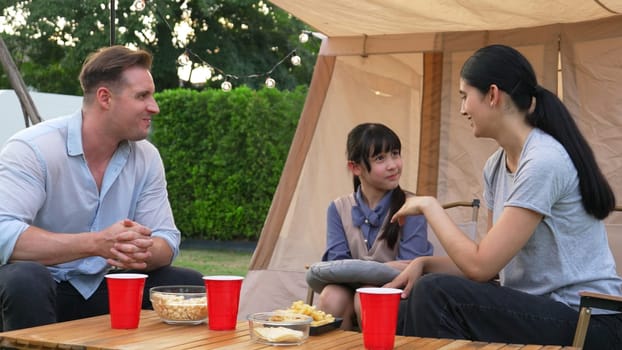 Family all together sit at camp in garden with tasty snack. Lovely parent use outdoor camping activity as way to communicate and spending time with young generation cross generation gap. Divergence.