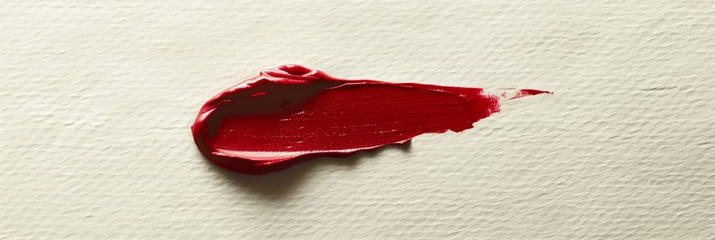 A up-close shot of a red lipstick smear on a white background, showcasing a bold and vibrant contrast.