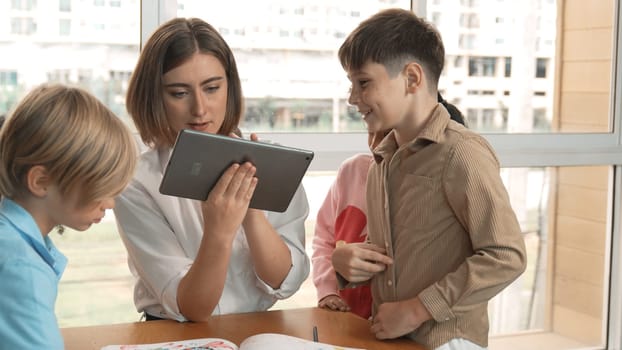 Smart teacher holding tablet while open online lesson to group of students. Skilled instructor explained engineering code lesson while young learner sitting and listening presentation. Erudition.