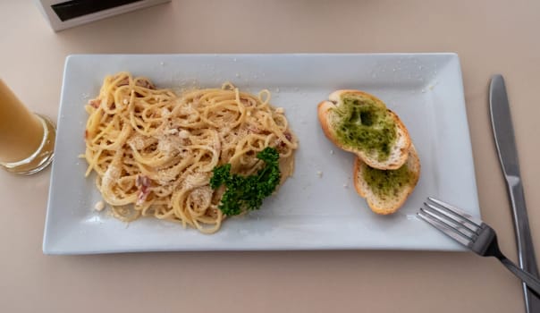 Delicious spaghetti carbonara with garlic bread and drink at an italian restaurant for lunch