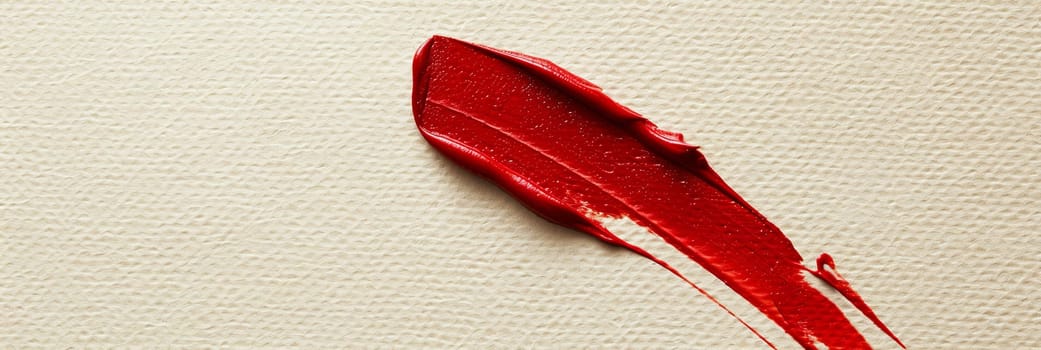 Close up of a vivid red lipstick stain on a pristine white surface.