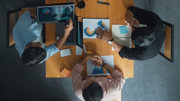 Top view of skilled project manager talking about financial graph to investors while sitting at meeting table with data analysis document. Diverse team discussing and brainstorming idea. Convocation.