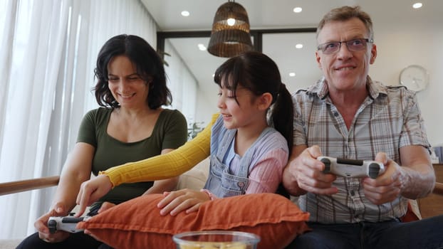 Grandfather, grandmother and granddaughter play console game as hobby. Old senior use technology activity communicate with new generation kid cross generation gap strengthen family bond. Divergence.