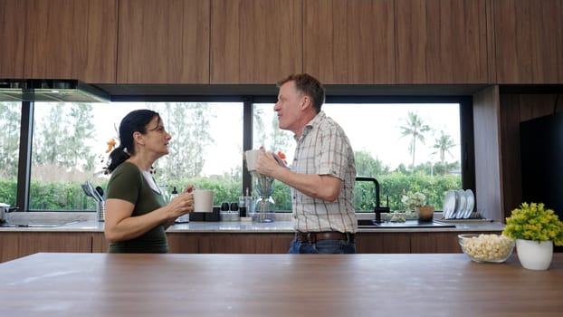 Lovely old marriage couple dancing in kitchen while listen entertaining music to celebrate good event or news. Cheerful grandfather and grandmother have happy relationship and family. Divergence.