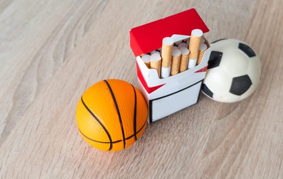 Smoking or sports. Sport ball and pack of cigarettes on table background. Top view. High quality photo