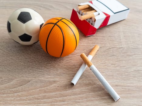 Smoking or sports. Sport ball and pack of cigarettes on table background. Top view. High quality photo