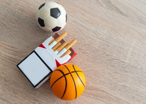 Smoking or sports. Sport ball and pack of cigarettes on table background. Top view. High quality photo