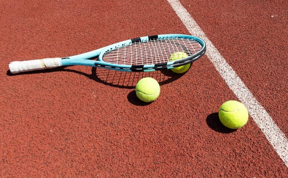 Racket with a tennis ball on a red clay court. High quality photo