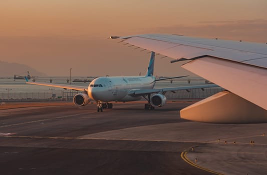 A commercial airplane is seen taxiing on the tarmac during a picturesque sunset at Hong Kong international airport.