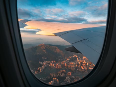 Aerial view of Hong Kong city buildings and river at sunset from airplane window