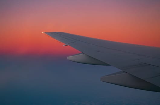 Airplane wing in flight during sunset with vibrant sky