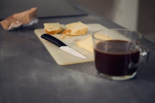 Still life with a breakfast on the kitchen table. Selective focus on a kitchen knife on the cutting board with sandwiches for lunch. Food background