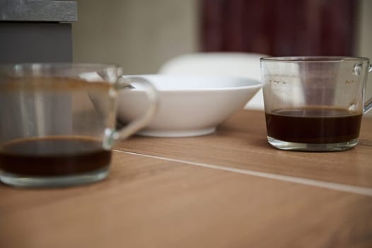 Close-up left over of breakfast in white ceramic bowl and two glass cups of unfinished coffee on the table. Food and drink consumerism