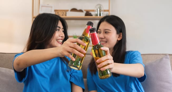 A lesbian couple cheers football and celebrate together for their favorite Euro football team. A young female couple cheers football on TV together in the living room on match day..