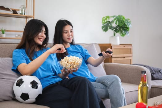 A lesbian couple cheers football and celebrate together for their favorite Euro football team. A young female couple cheers football on TV together in the living room on match day..