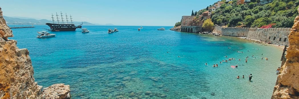 Banner of the wall of the old Alanya fortress to a beautiful beach and ships, soft focus. concept of summer vacation, beach holiday