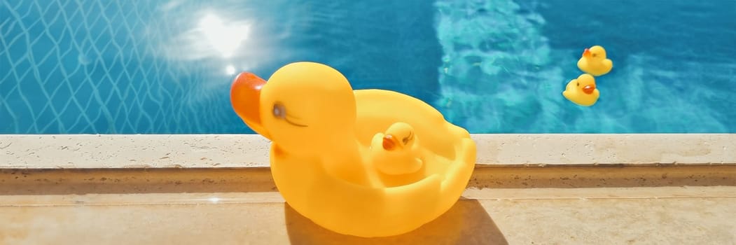 Banner of yellow rubber duck near a pool with blue water. beach holiday concept. soft focus. copy space