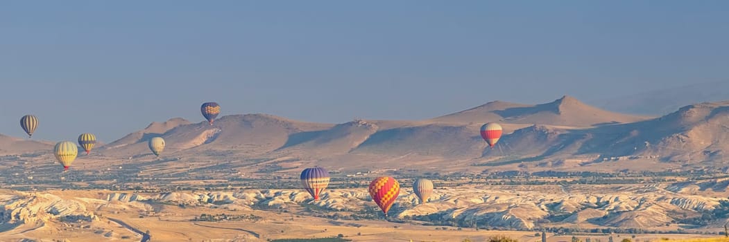 Banner of Cappadocia Turkey 08.01.2021 Large colored hot air balloons fly against the backdrop of mountain landscapes at sunrise early in the morning. soft focus