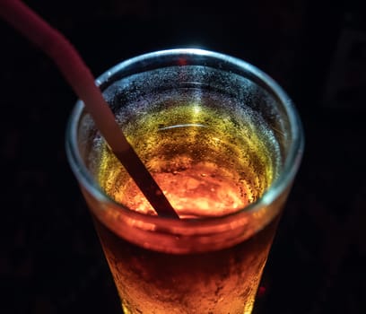 Close-up of refreshing chilled cocktail with straw in dimly lit bar at night