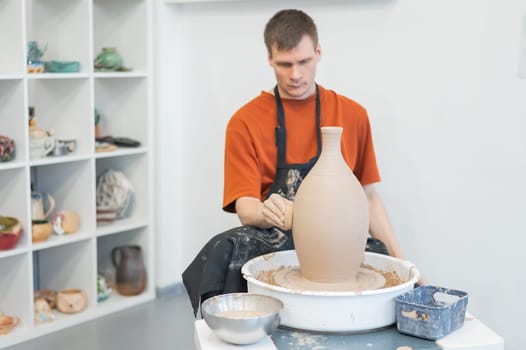 A potter works on a potter's wheel to smooth the surface of a vase